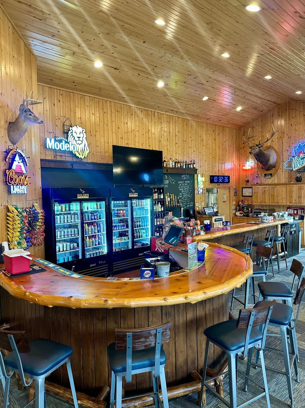 Curved wood-topped bar with stocked beverage coolers and bar stools at the Golden Eagle clubhouse
