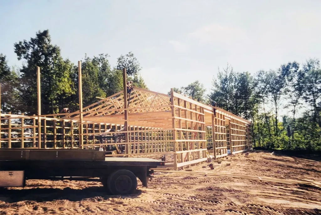The Golden Eagle clubhouse during summer framing, wood trusses rising against the Northwoods treeline