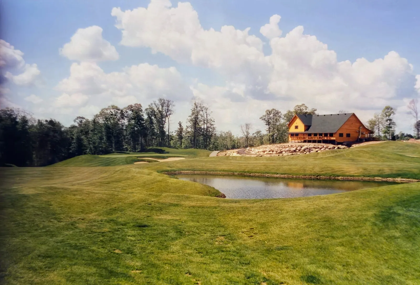 Golden Eagle clubhouse with pond and green in the foreground on a summer day