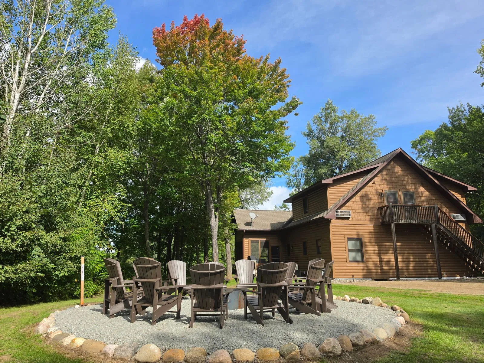 Adirondack chairs circled around the stone-ringed fire pit behind the Golden Eagle Cottage, under tall maples just starting to turn