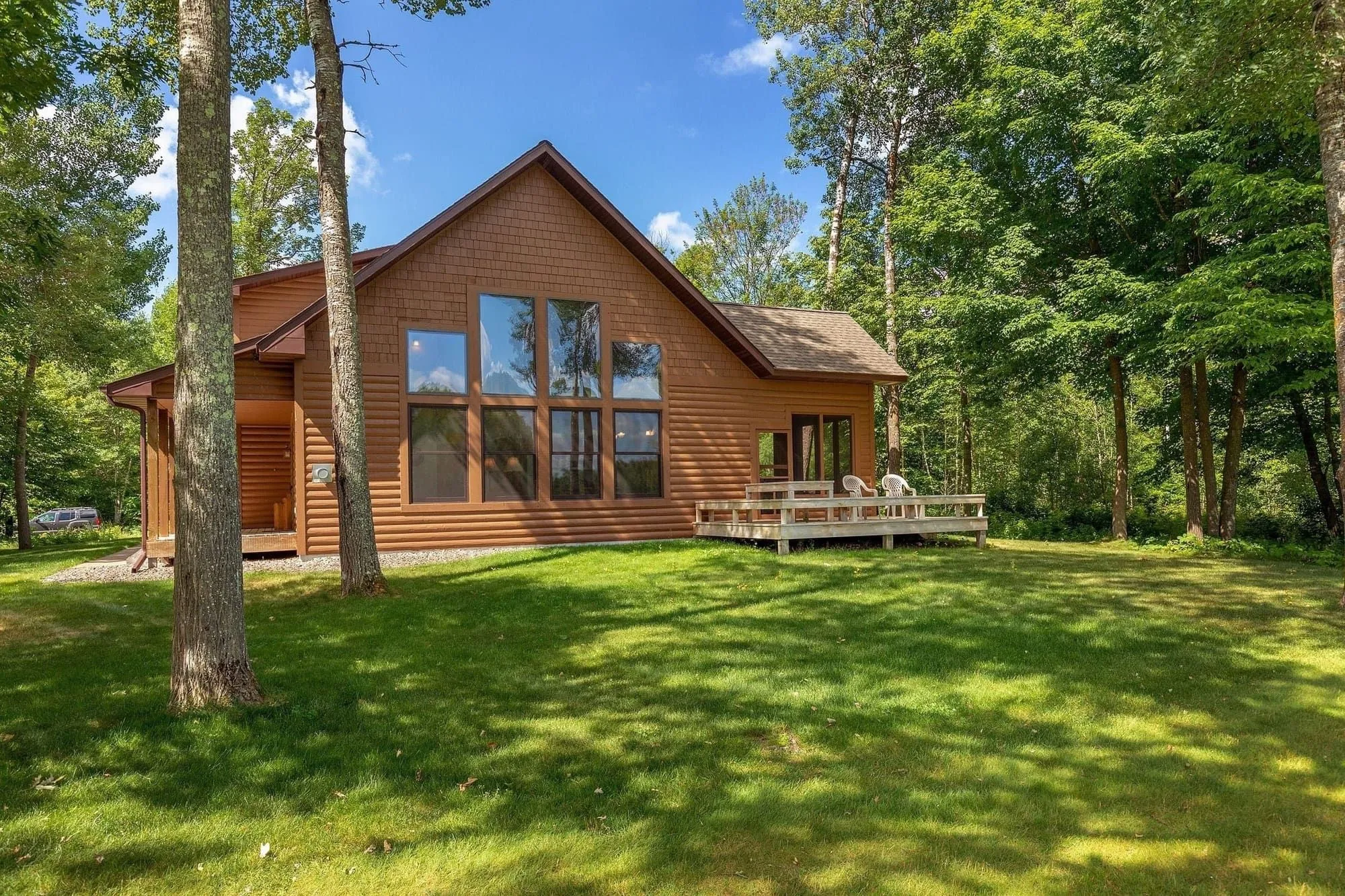 Exterior of the Golden Eagle Cottage with green lawn and Northwoods trees behind