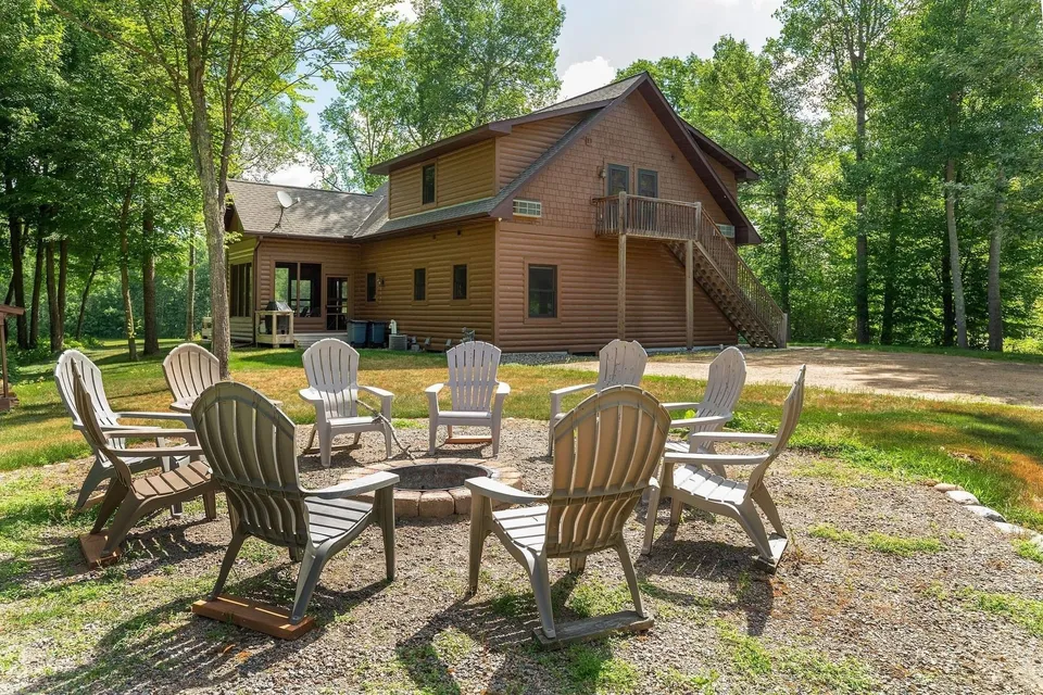 Outdoor fire pit ringed with Adirondack chairs outside the Golden Eagle Cottage, set among the trees