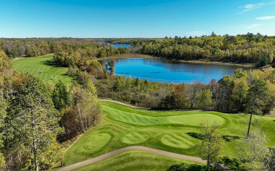 Wide fairway sweeping toward an elevated green framed by mature pines