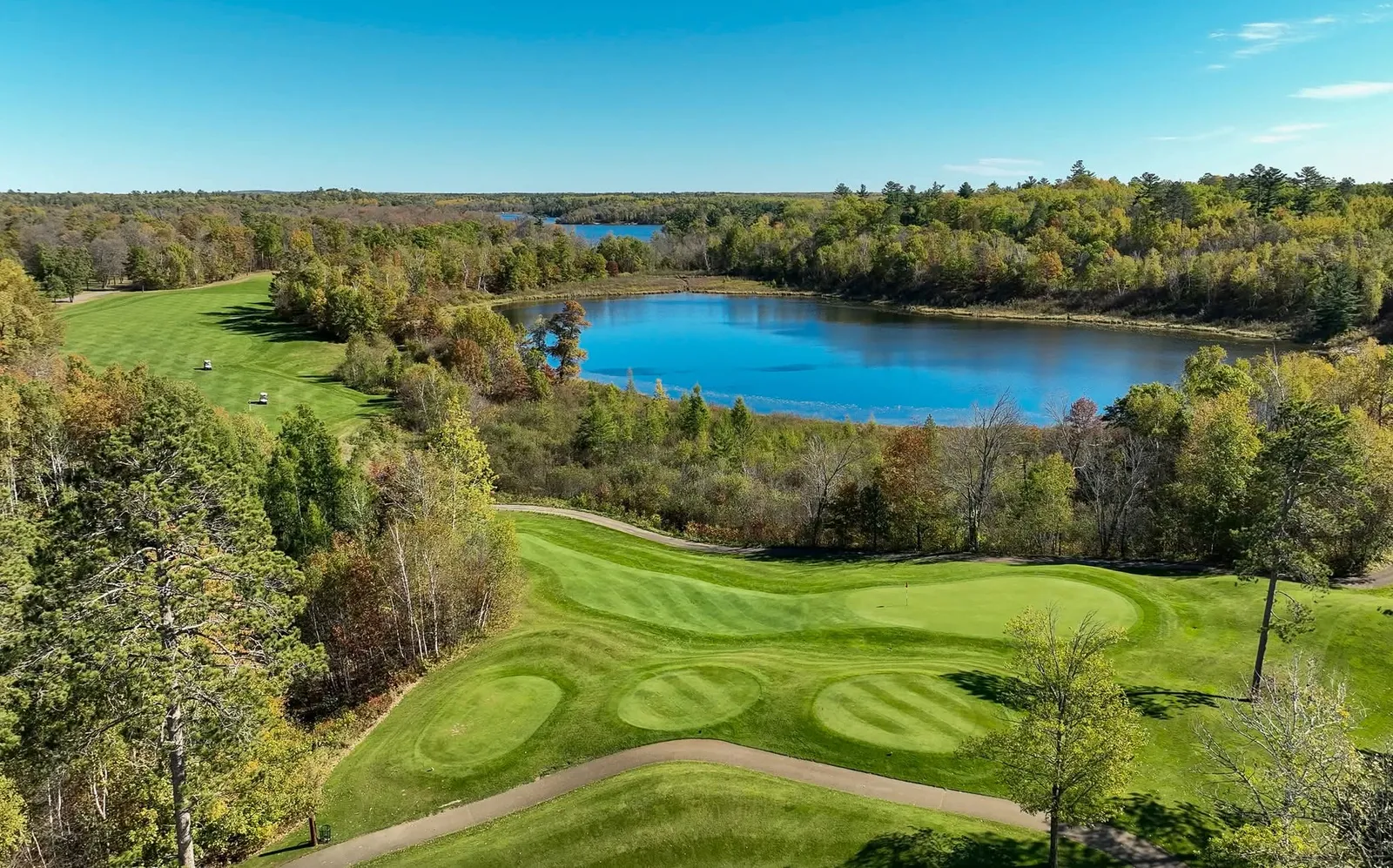 Wide fairway sweeping toward an elevated green framed by mature pines