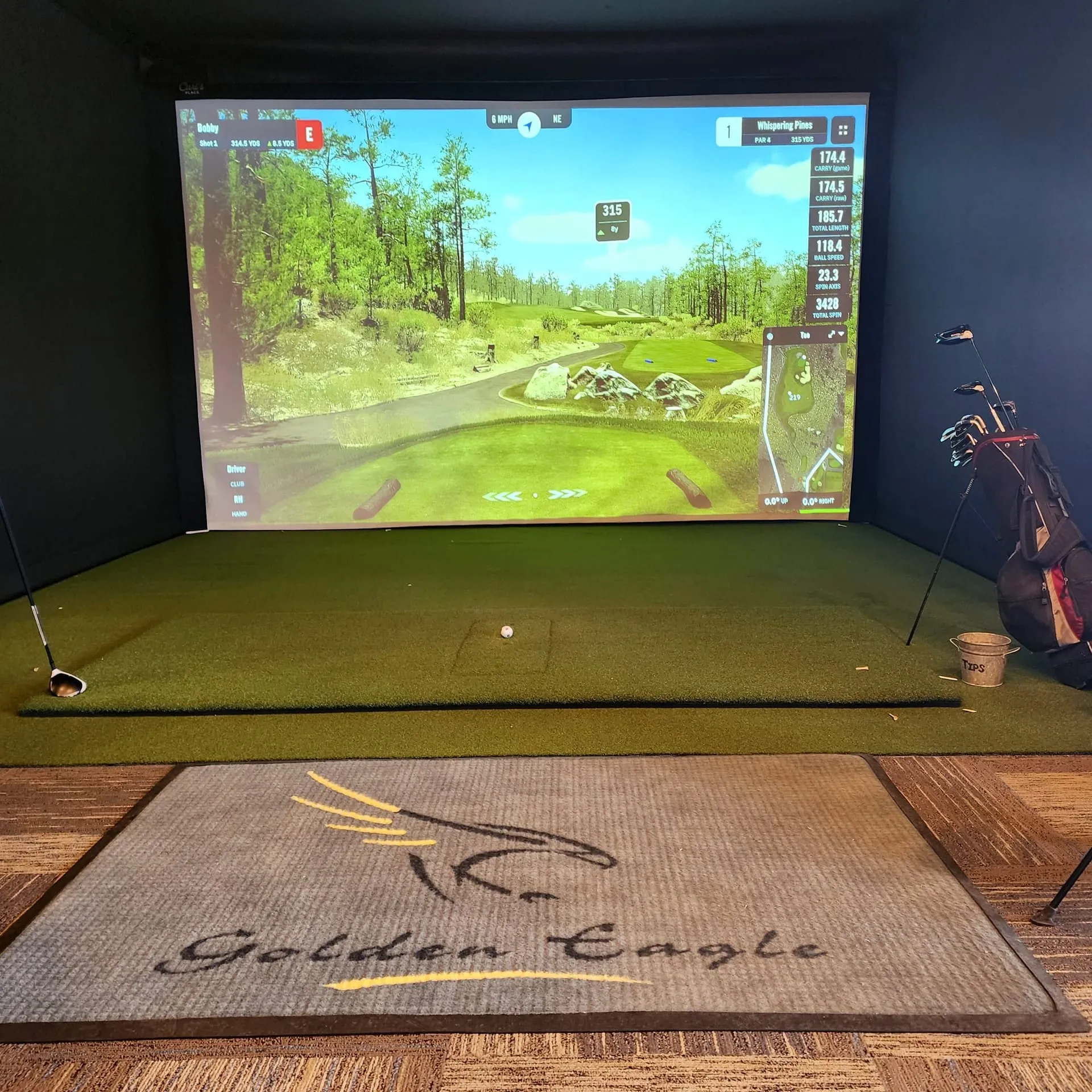 Wide view of the upstairs simulator lounge showing the screen, hitting area, and lounge seating