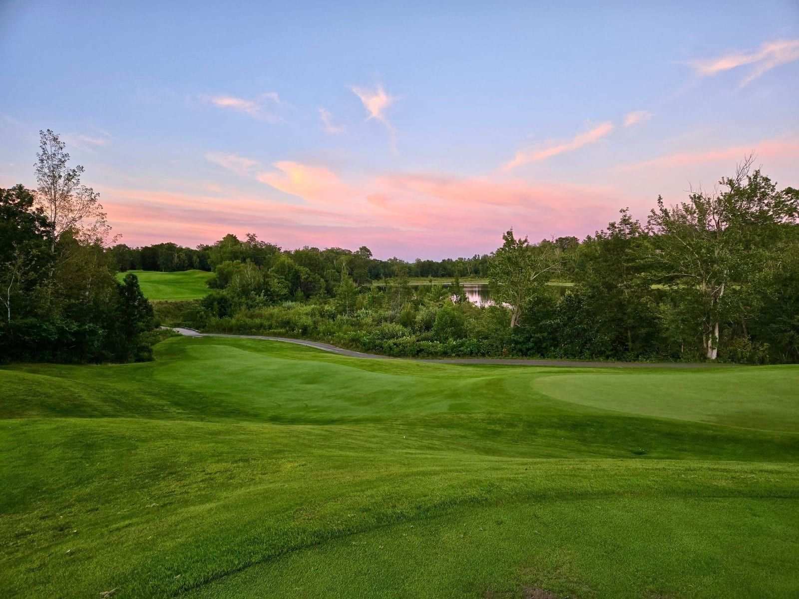 Sweeping Golden Eagle fairway bathed in Northwoods afternoon light with Eagle Lake in the distance