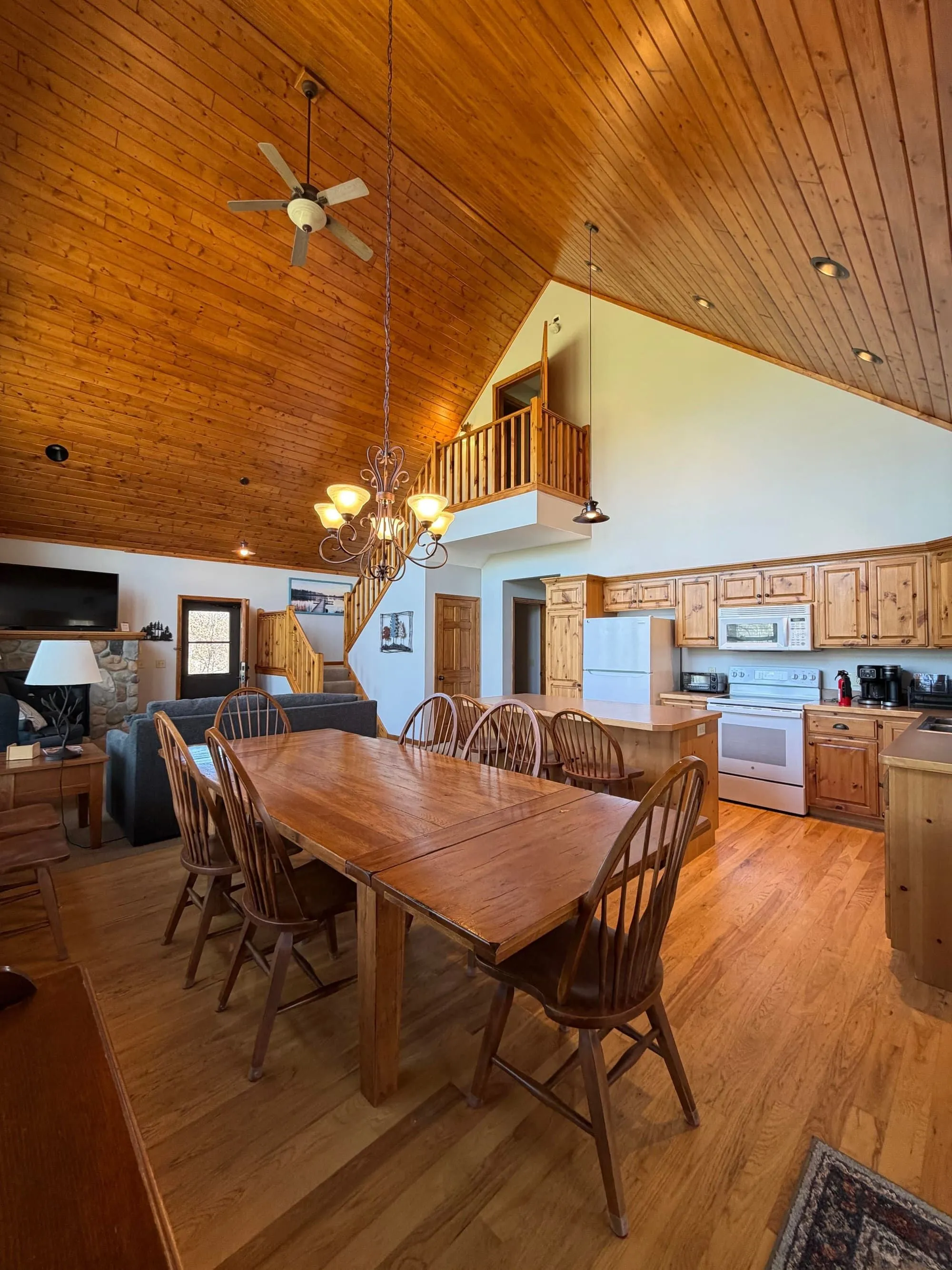 Overhead view of the Golden Eagle Cottage's open kitchen and long dining table set under the vaulted pine ceiling